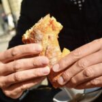 Uomo che mangia un panino al bar