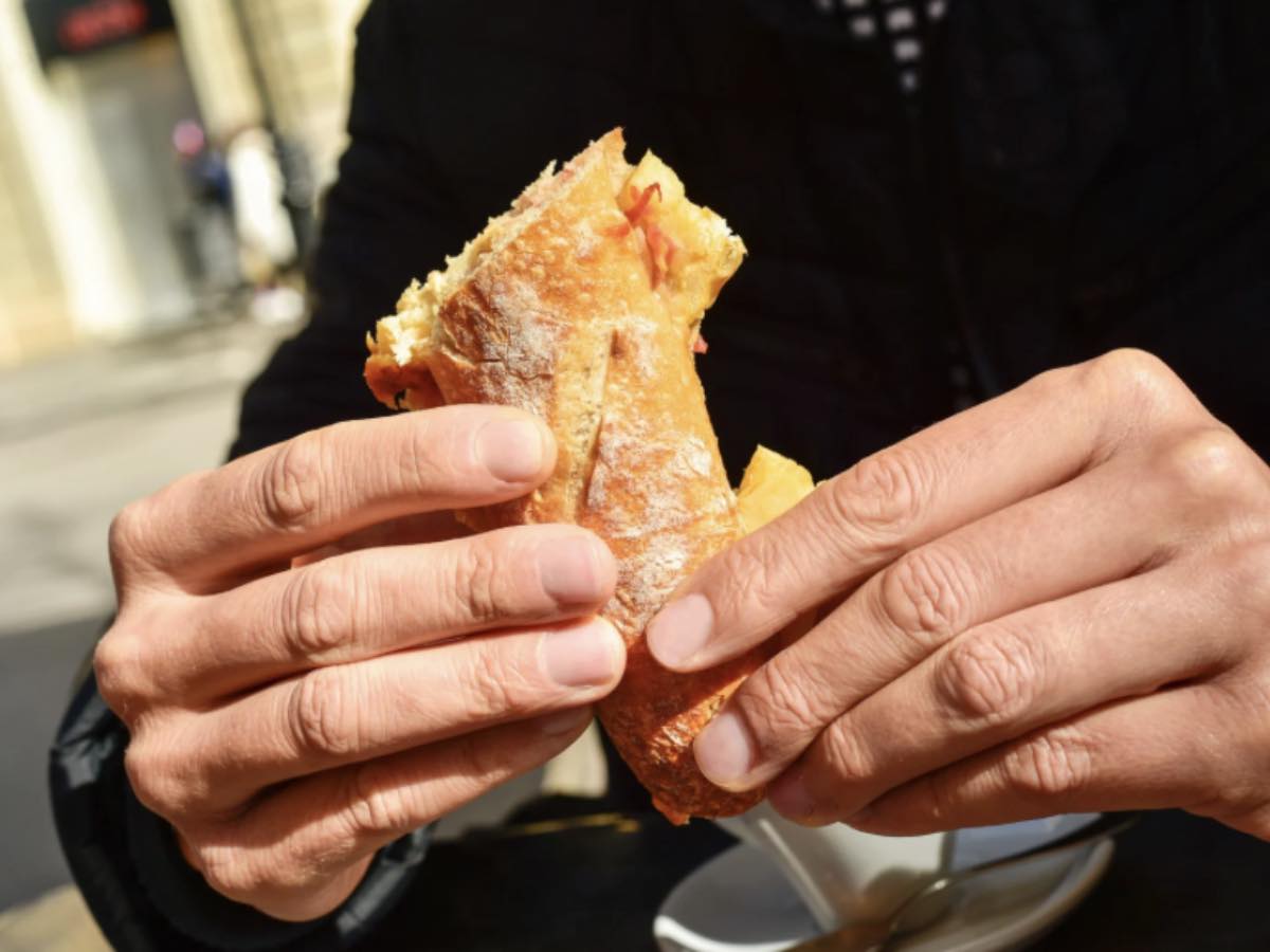 Uomo che mangia un panino al bar