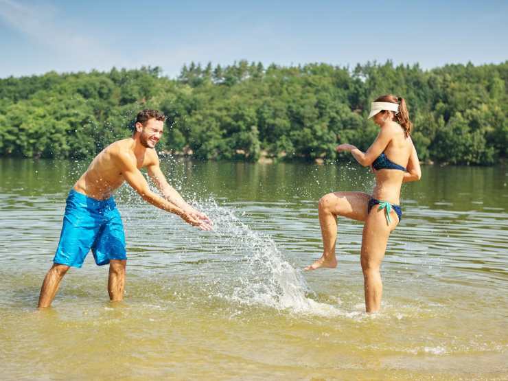 ragazzo e ragazza si schizzano nell'acqua del lago