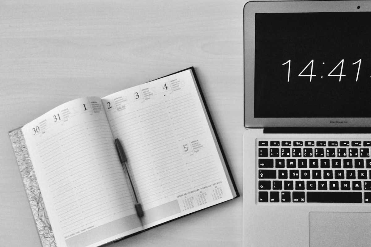 Agenda aperta con penna e laptop sulla scrivania