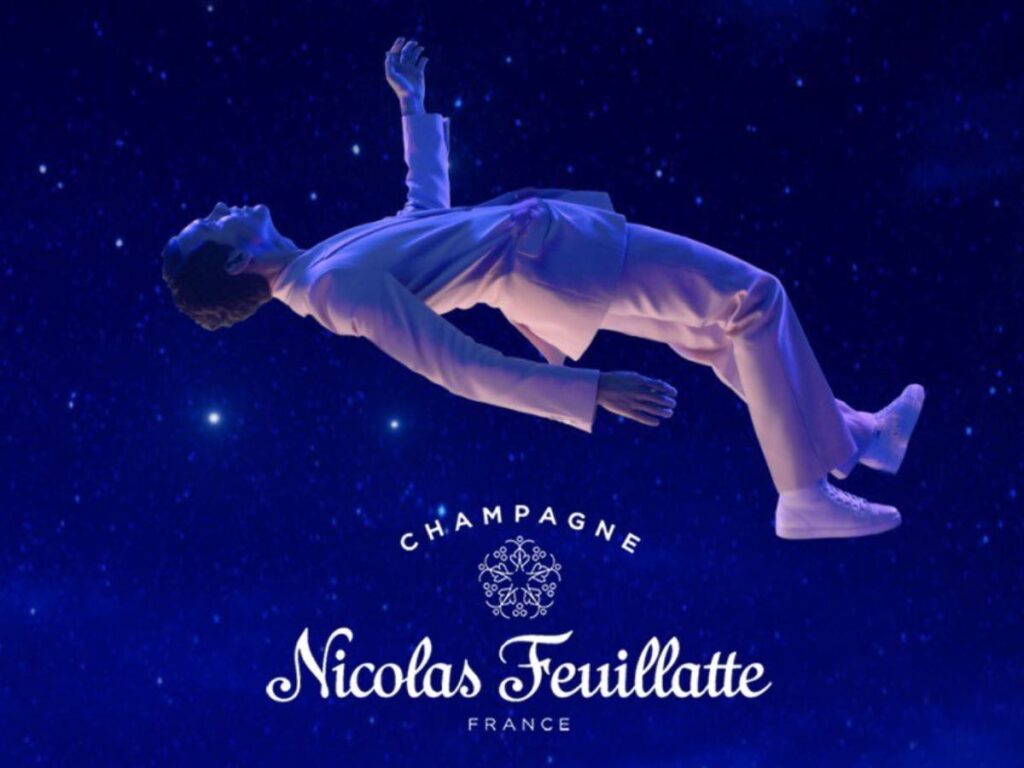 Mika che fluttua sopra il logo di Nicolas Feuilatte